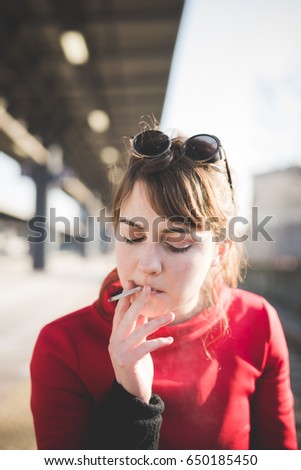 young beautiful red dressed vintage hipster woman at the station smoking cigarette