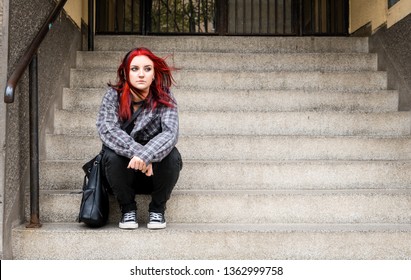 Young Beautiful Red Hair Girl Sitting Alone Outdoors On The Stairs Of The Building With Hat And Shirt Feeling Anxious And Depressed After She Became A Homeless Person