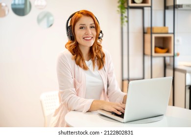 Young beautiful redhead customer service operator woman with headphones working from home. Internet communication, customer support, online meeting concept