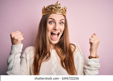 Young beautiful redhead woman wearing queen crown over isolated pink background celebrating surprised and amazed for success with arms raised and open eyes. Winner concept.