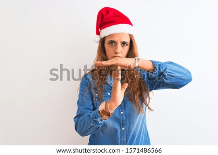 Young beautiful redhead woman wearing christmas hat over isolated background Doing time out gesture with hands, frustrated and serious face