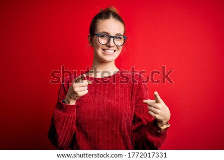 Young beautiful redhead woman wearing casual sweater over isolated red background pointing fingers to camera with happy and funny face. Good energy and vibes.