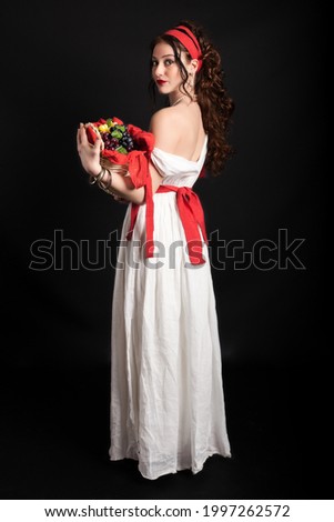 Young beautiful roman nymph goddess woman model wearing ancient white and red greek cotume in classic statue poses photo in studio