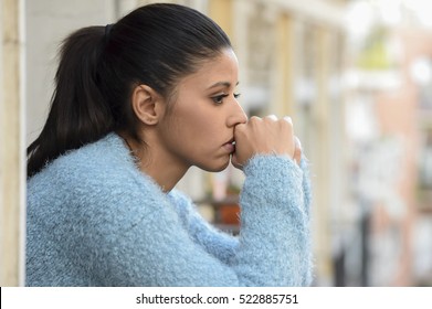 junge schöne traurige und verzweifelte hispanische Frau, die unter Depression leidet, gedankenvoll und frustriert auf dem Wohnbalkon Blick deprimiert auf die Straße 
