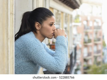 junge schöne traurige und verzweifelte hispanische Frau, die unter Depression leidet, gedankenvoll und frustriert auf dem Wohnbalkon Blick deprimiert auf die Straße 