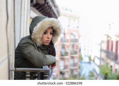 Young Beautiful Sad And Desperate Hispanic Woman In Winter Coat Suffering Depression Looking Thoughtful And Frustrated At Apartment Balcony Looking Depressed At The Street 
