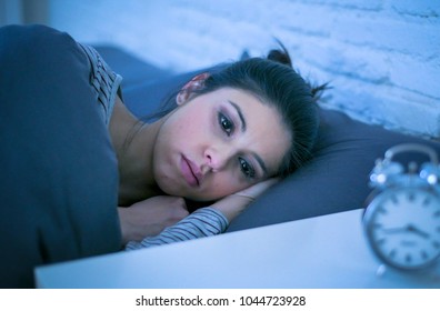 young beautiful sad and worried latin woman suffering insomnia and sleeping disorder problem unable to sleep late at night lying on bed awake feeling stressed and frustrated