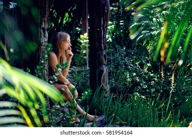 Young Beautiful And Sexy Girl Standing In The Garden And Holding A Palm Frond.