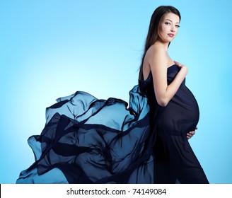 Young beautiful sexy and stylish  pregnant woman in blue - blue background