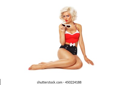 Young beautiful sexy tanned blonde woman in vintage bath costume and sunglasses in her hand over white background