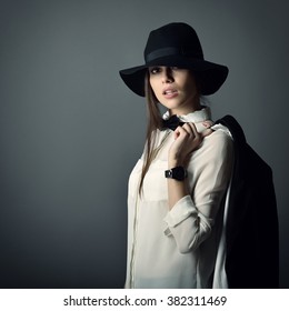 Young Beautiful Sexy Woman In Jacket, White Shirt, Bow-tie And Hat Over Gray Background. Fashion Female Portrait. Tomboy. Girl Gets On Men's Clothes.