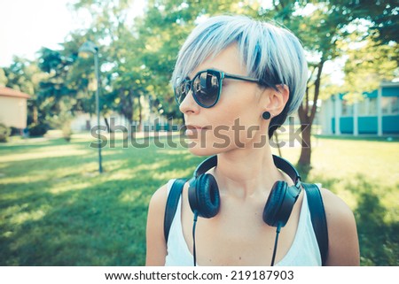 young beautiful short blue hair hipster woman with headphones music in the city