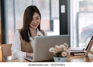 Young Beautiful Smiling Asian Business Woman Holding A Coffee And Laptop Placed At The Wooden Table At The Office