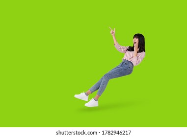 Young beautiful smiling asian girl hand pointing up to copy space isolated on green background. 