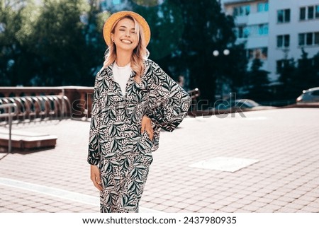 Young beautiful smiling blond hipster woman in trendy summer hippie costume clothes. Carefree female posing in the street at sunny day. Positive model outdoors at sunset. Cheerful and happy in hat