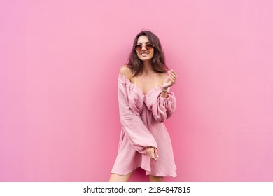 Young beautiful smiling cute romantic woman in trendy summer dress. Carefree woman posing in the street near pink wall. Positive model outdoors in sunglasses. Cheerful and happy
 - Powered by Shutterstock