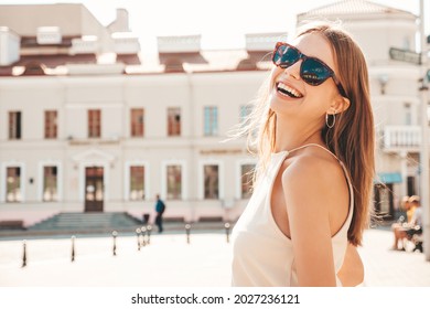 Young beautiful smiling hipster woman in trendy summer clothes. Sexy carefree woman posing on the street background at sunset. Positive model outdoors. Cheerful and happy in sunglasses