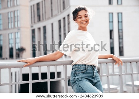 Young beautiful smiling hipster woman in trendy summer white t-shirt and jeans clothes. Carefree woman, posing in the street at sunny day. Positive model outdoors