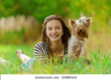 Young beautiful smiling woman with Yorkshire Terrier, against green of summer park. - Powered by Shutterstock