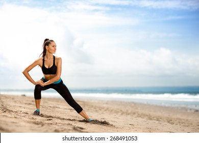 young beautiful sportswoman doing exercises on beach 