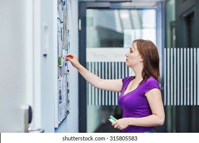 Young Beautiful Student At College Or University Using Notice Board