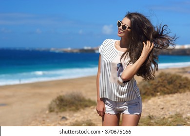 Young beautiful stylish girl posing at beach on a windy day