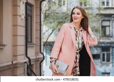 young beautiful stylish woman walking in street in pink coat, floral printed dress, holding silver purse in hands, autumn fashion trend, smiling, happy - Powered by Shutterstock