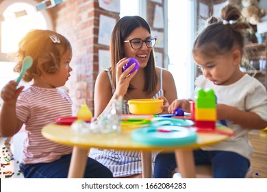 Young beautiful teacher and toddlers playing meals using plastic food and cutlery toy at kindergarten - Shutterstock ID 1662084283