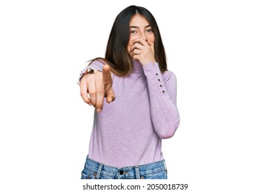 Young Beautiful Teen Girl Wearing Turtleneck Sweater Laughing At You, Pointing Finger To The Camera With Hand Over Mouth, Shame Expression 