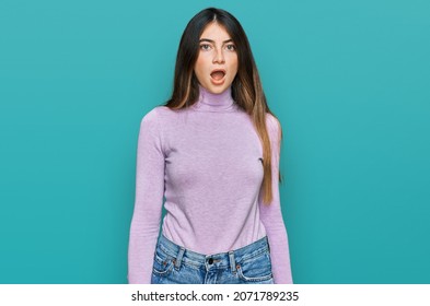 Young Beautiful Teen Girl Wearing Turtleneck Sweater In Shock Face, Looking Skeptical And Sarcastic, Surprised With Open Mouth 