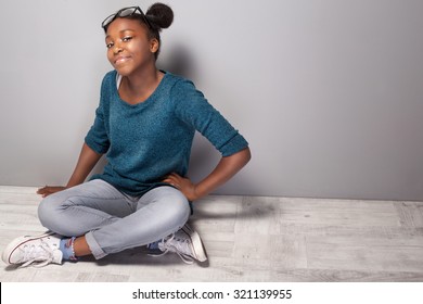 Young beautiful teenage girl sitting on the floor. Girl with eyeglasses on head looking at camera, smiling.
