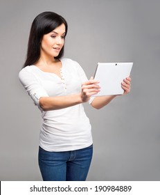 Young And Beautiful Teenager Girl Holding An Ipad Tablet Pc In Her Arms Over Grey Background