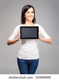 Young And Beautiful Teenager Girl Holding An Ipad Tablet Pc In Her Arms Over Grey Background