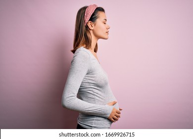 Young Beautiful Teenager Girl Pregnant Expecting Baby Over Isolated Pink Background Looking To Side, Relax Profile Pose With Natural Face And Confident Smile.