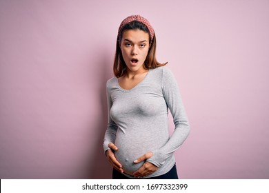 Young Beautiful Teenager Girl Pregnant Expecting Baby Over Isolated Pink Background In Shock Face, Looking Skeptical And Sarcastic, Surprised With Open Mouth