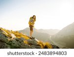 Young beautiful tourist woman enjoys beautiful nature while standing on top of the hill. Nature, travel, sport, active lifestyle.