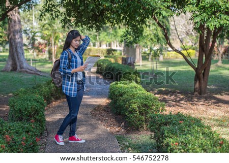 Young beautiful traveler woman with Travel map and backpack in the park.