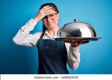 Young Beautiful Waitress Woman With Blue Eyes Holding Tray With Dome Over Isolated Background Stressed With Hand On Head, Shocked With Shame And Surprise Face, Angry And Frustrated. Fear And Upset 