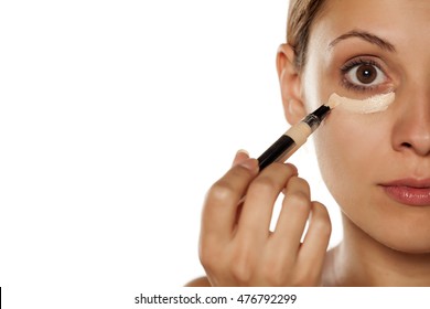 young beautiful woman applied concealer under the eyes - Shutterstock ID 476792299