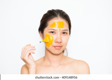 Junge schöne Frau, die Jogurt und turmerische Gesichtsmaske anwendet Hautpflege, Schönheitsbehandlungen auf weißem Hintergrund