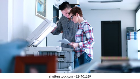 Young Beautiful Woman with assistant Making Copies Of Files In The Copy Machine