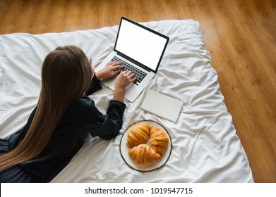 young beautiful Woman in bed typing on computer