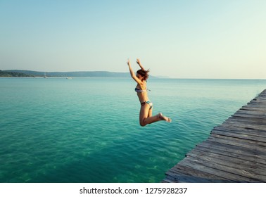 Young beautiful woman in bikini jumping into the turquoise sea, summer, vacation travel to tropical countries, adventure and freedom