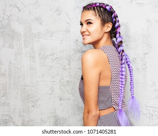 Young Beautiful Woman With Braids Posing In Profile On A Gray Background In A Fashionable Summer Outfit. Indoor. Close Up.