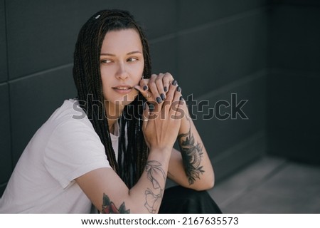 Young beautiful woman with braids and tatoos posing in the city