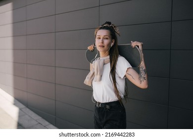 Young beautiful woman with braids and tattoos wearing casual clothes standing with skateboard on city street. - Powered by Shutterstock