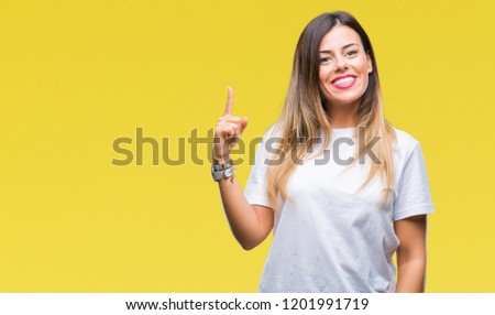 Young beautiful woman casual white t-shirt over isolated background pointing finger up with successful idea. Exited and happy. Number one.