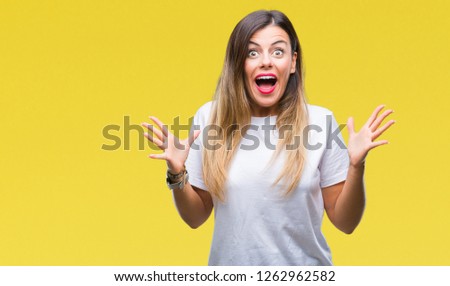 Young beautiful woman casual white t-shirt over isolated background celebrating crazy and amazed for success with arms raised and open eyes screaming excited. Winner concept