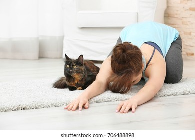 Young Beautiful Woman With Cat Practicing Yoga Pose At Home