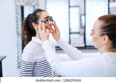 Young beautiful woman checking her sight at ophthalmologist. On eyes phoropter.